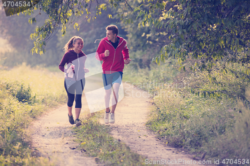 Image of young couple jogging along a country road