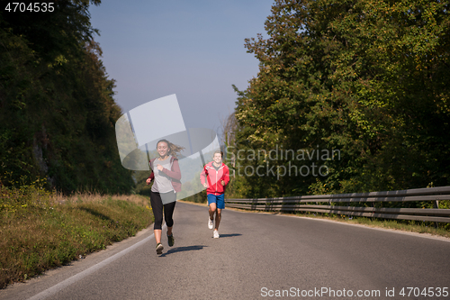 Image of young couple jogging along a country road