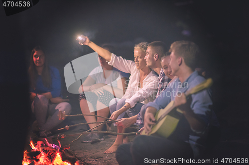 Image of young friends relaxing around campfire