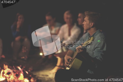 Image of young friends relaxing around campfire