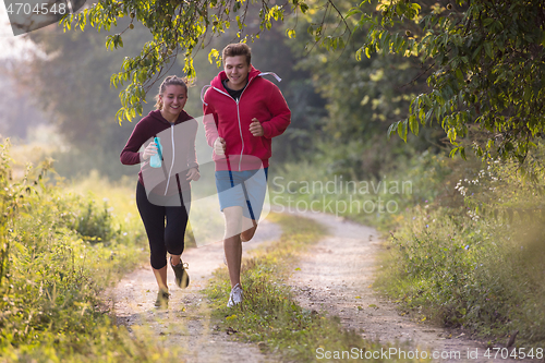 Image of young couple jogging along a country road