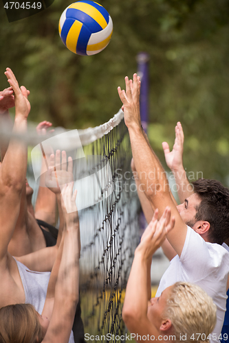 Image of group of young friends playing Beach volleyball