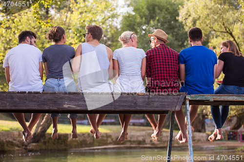 Image of rear view of friends enjoying watermelon while sitting on the wo