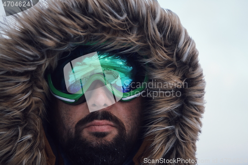 Image of man at winter in stormy weather wearing warm fur jacket