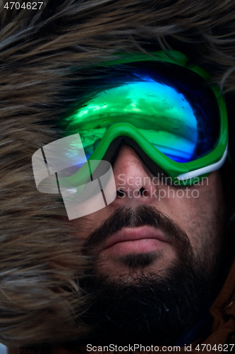 Image of man at winter in stormy weather wearing warm fur jacket