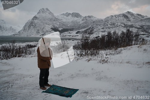 Image of Muslim traveler praying in cold snowy winter day