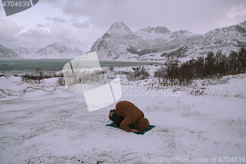 Image of Muslim traveler praying in cold snowy winter day