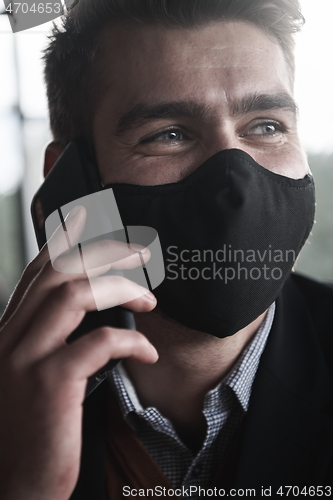 Image of business man wearing coronavirus medical face mask while using smartphone