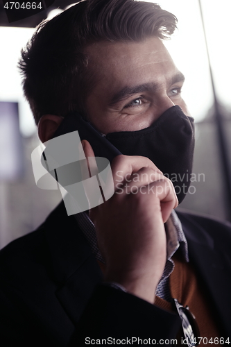 Image of business man wearing coronavirus medical face mask while using smartphone