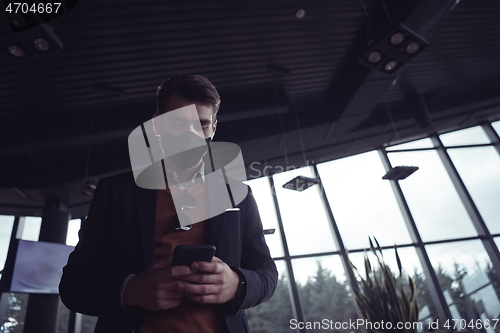 Image of business man wearing coronavirus medical face mask while using smartphone