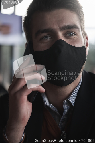 Image of business man wearing coronavirus medical face mask while using smartphone