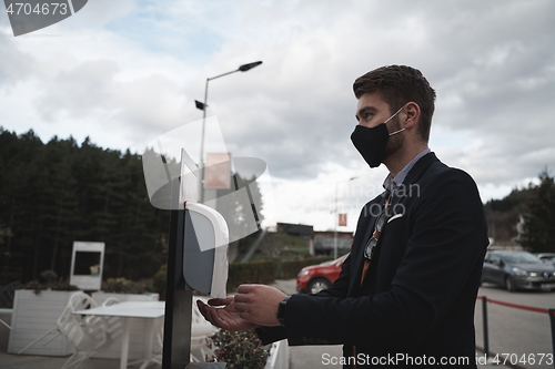 Image of guest using hands disinfection in restaurant