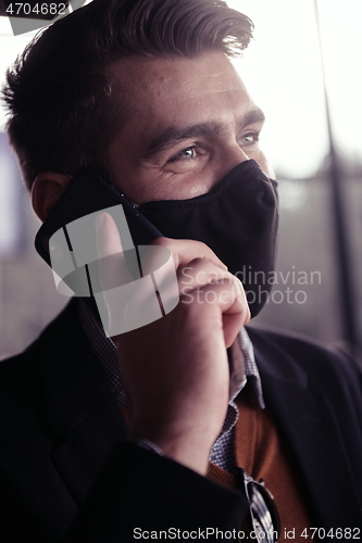 Image of business man wearing coronavirus medical face mask while using smartphone