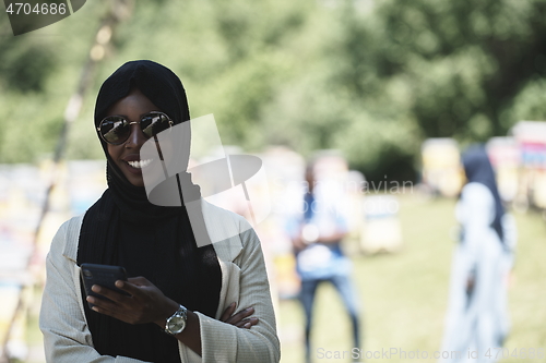 Image of african woman using smartphone wearing traditional islamic clothes