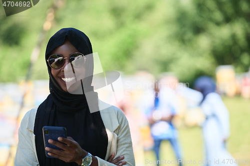 Image of african woman using smartphone wearing traditional islamic clothes