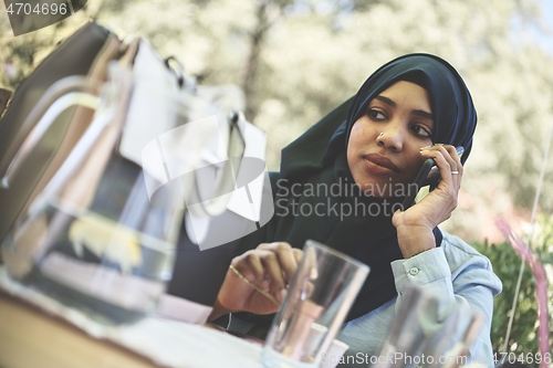 Image of african woman using smartphone wearing traditional islamic clothes