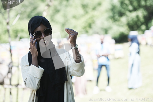 Image of african woman using smartphone wearing traditional islamic clothes