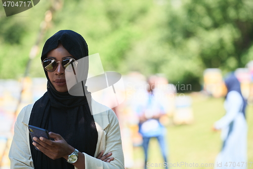 Image of african woman using smartphone wearing traditional islamic clothes