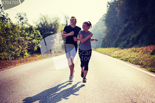 Image of young couple jogging along a country road