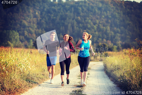 Image of young people jogging on country road