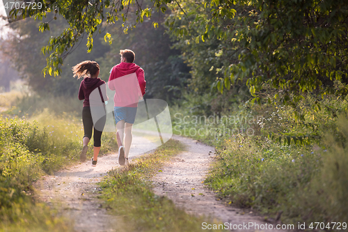 Image of young couple jogging along a country road