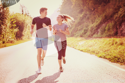 Image of young couple jogging along a country road