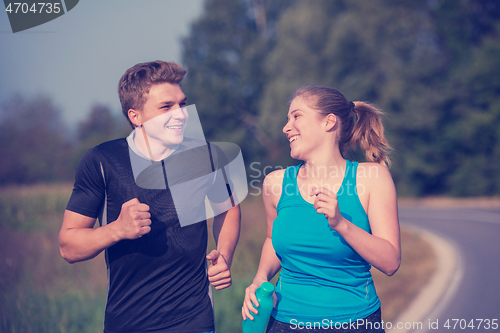 Image of young couple jogging along a country road