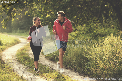 Image of young couple jogging along a country road