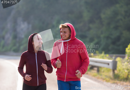 Image of young couple jogging along a country road
