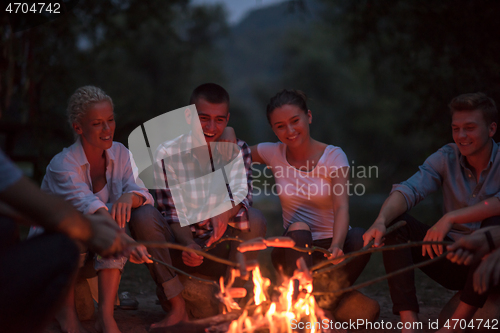 Image of young friends relaxing around campfire