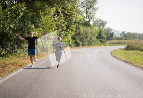 Image of young couple jogging along a country road