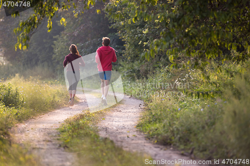 Image of young couple jogging along a country road