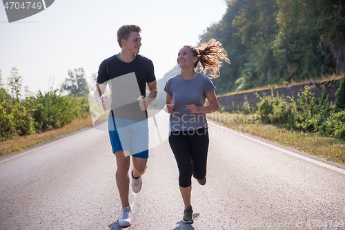 Image of young couple jogging along a country road