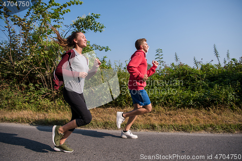 Image of young couple jogging along a country road