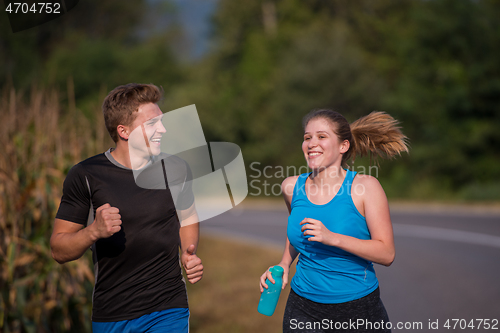 Image of young couple jogging along a country road