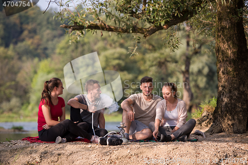 Image of friends smoking hookah on the river bank