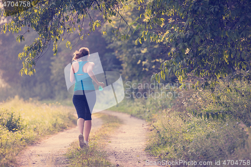 Image of woman jogging along a country road