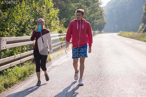 Image of young couple jogging along a country road