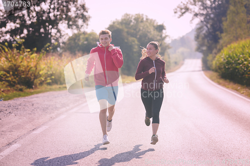 Image of young couple jogging along a country road