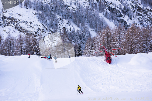 Image of rescue team with a red helicopter rescuing a hurt skier