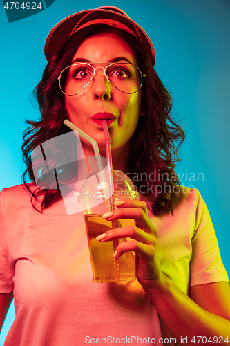 Image of Happy young woman standing and smiling against blue background