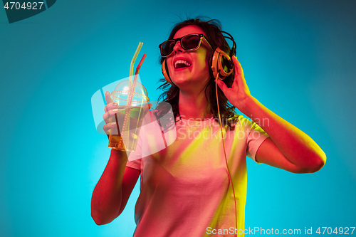 Image of Happy young woman standing and smiling against blue background