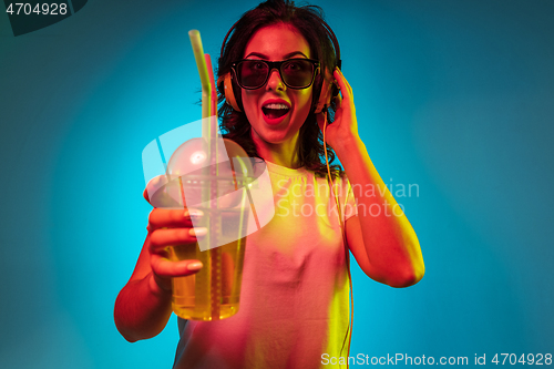 Image of Happy young woman standing and smiling against blue background