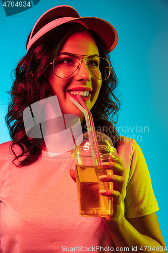 Image of Happy young woman standing and smiling against blue background