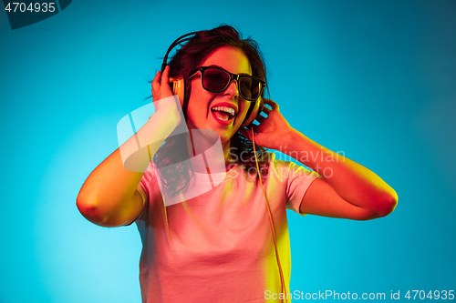 Image of Happy young woman standing and smiling against blue background