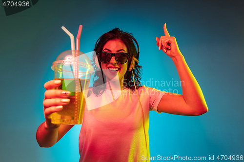 Image of Happy young woman standing and smiling against blue background