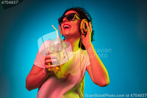 Image of Happy young woman standing and smiling against blue background