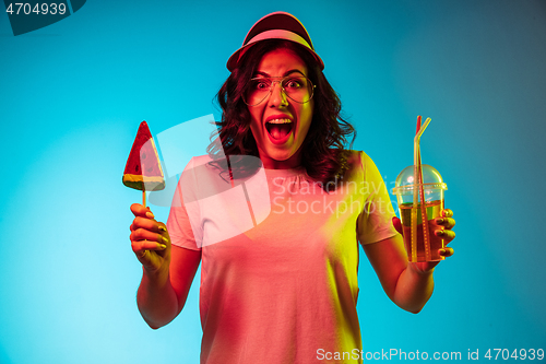 Image of Happy young woman standing and smiling against blue background