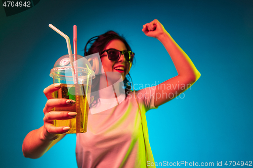 Image of Happy young woman standing and smiling against blue background