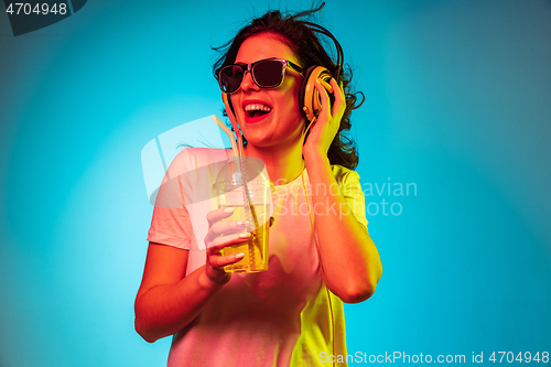 Image of Happy young woman standing and smiling against blue background